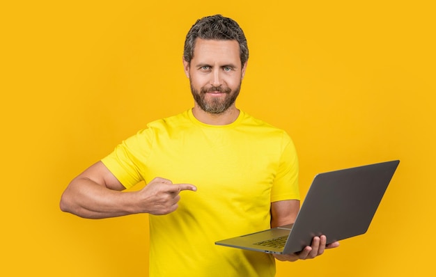 Man programmer on background point finger man programmer in studio photo of man programmer with laptop man programmer isolated on yellow