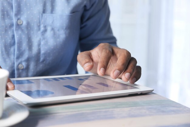 man's hand working on digital tablet at office desk using self created chart