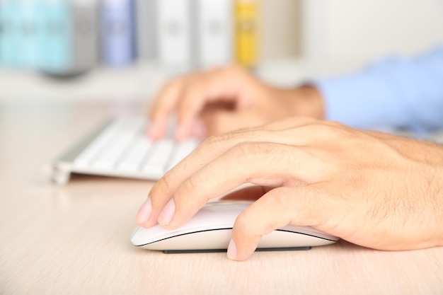 man working with keyboard on wooden table on folders background closeup