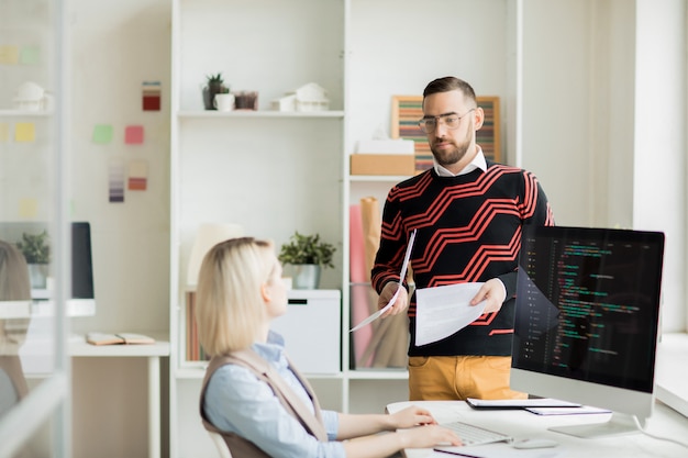 Manager giving paper with task to coding specialist