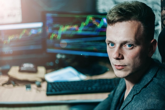 Mandlig børsmægler sidder ved en computer og ser diagrammet over ændringer i valutakursen an