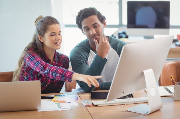 Mandlige og kvindelige grafiske designere diskuterer over en computer
