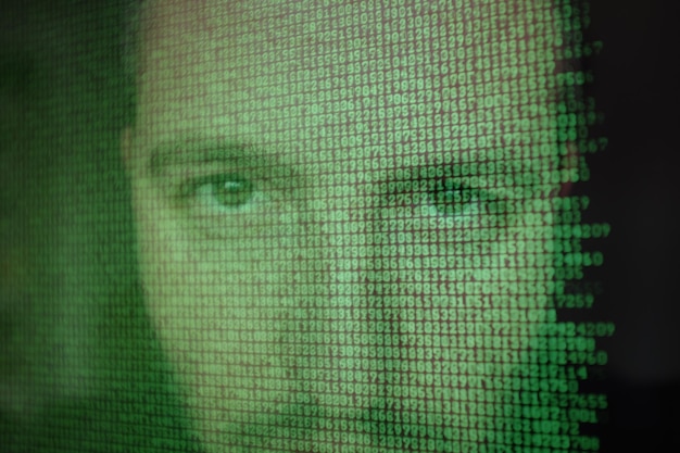 Mans face reflected in computer screen with binary code
