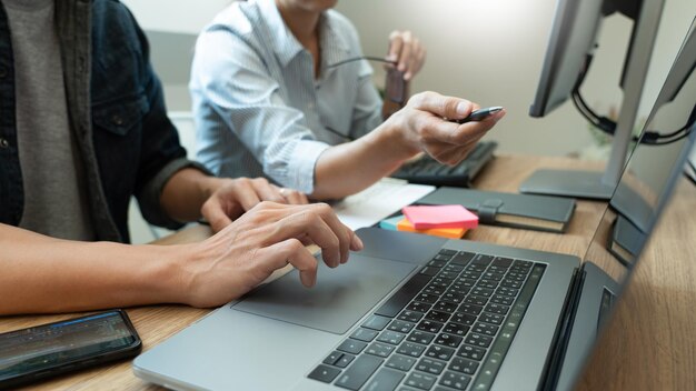 Midsection of colleagues discussing over laptop in office