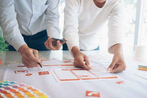 Midsection of colleagues with arranging notes on office desk