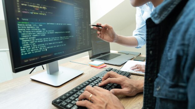 Midsection of coworkers coding over computer in office