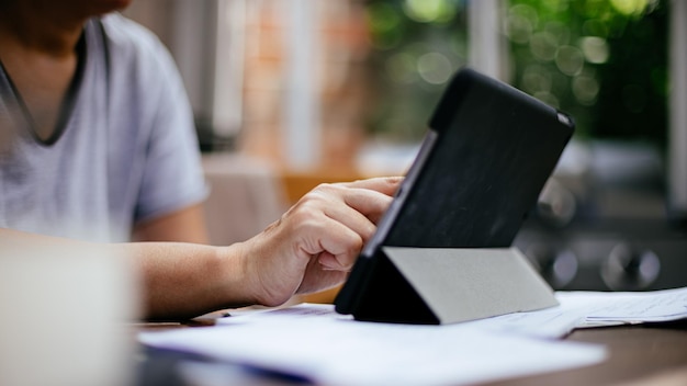 Midsection of man using digital tablet at cafe