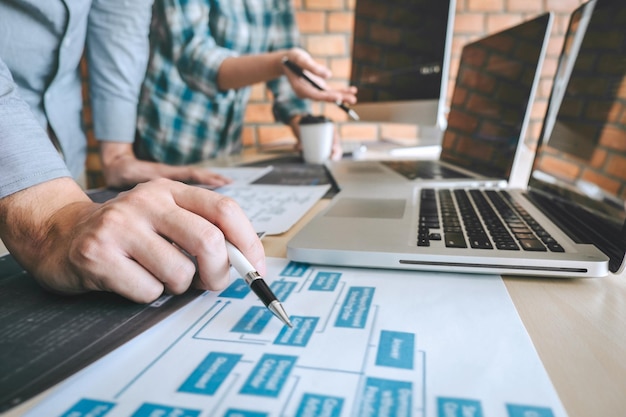 Midsection of programmers working on table