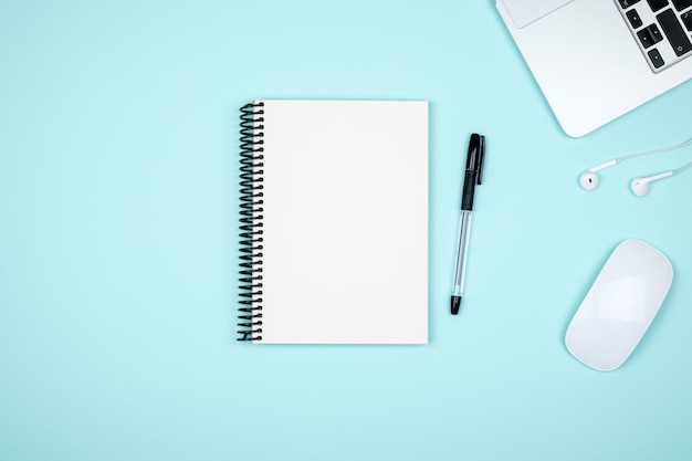 Minimalistisk arbejdsplads med bærbar computer og blank notesblok