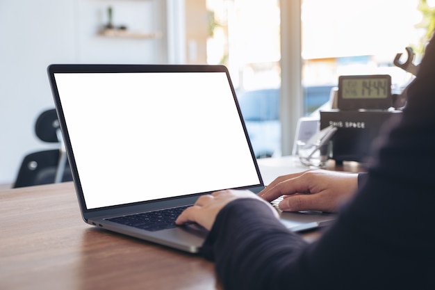 Mockup billede af en kvinde, der bruger og skriver på bærbar computer med tom hvid skrivebordsskærm