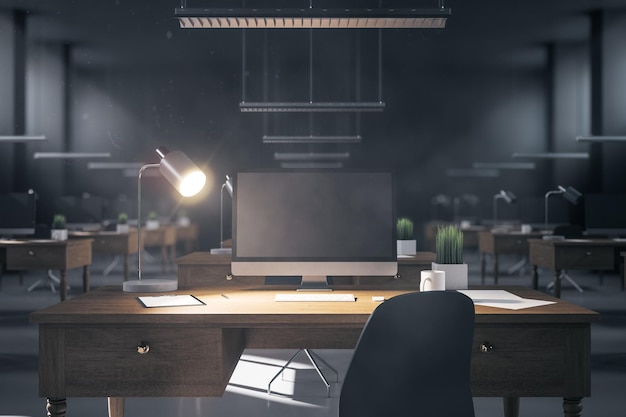 Modern coworking night office interior with computers on table with blank screen