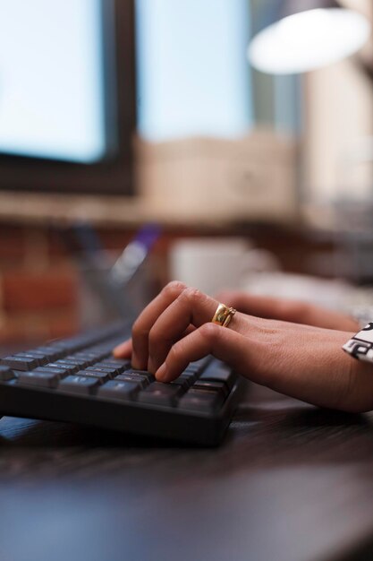 Nærbillede af reklamevirksomhed forretningskvindes hænder, der skriver på tastaturet, mens hun arbejder på forretningsprojekt ved hjælp af arbejdscomputer. Bureau kontormedarbejder på computer udvikler marketingstrategi.