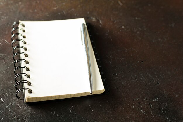 Notebook with pen on brown background