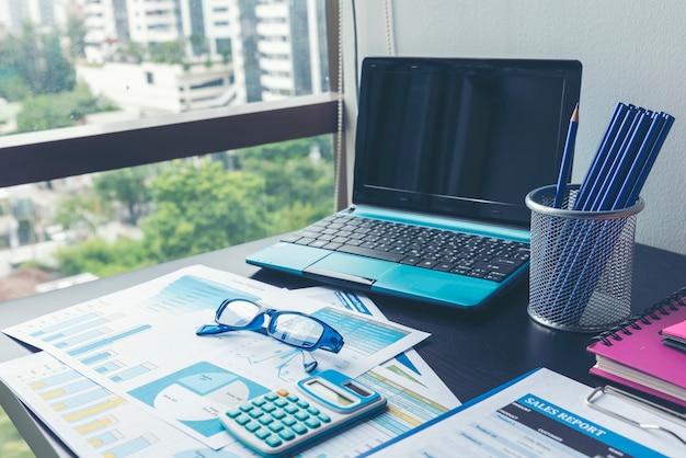 Office laptop business financial document chart and graph on wooden table with coffee cup