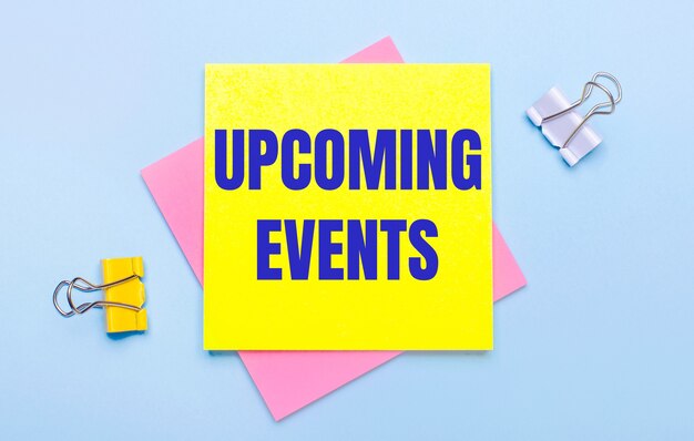 On a light blue background, there are yellow and white paper clips, pink and yellow sticky notes with the text UPCOMING EVENTS