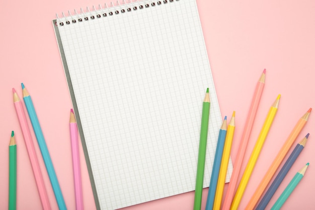 open notebook with colorful pencil on pink background