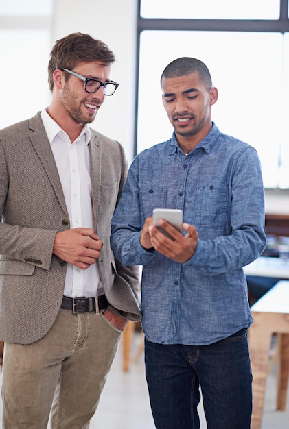 our online platform is looking good shot of two coworkers standing in an office looking at a digital tablet