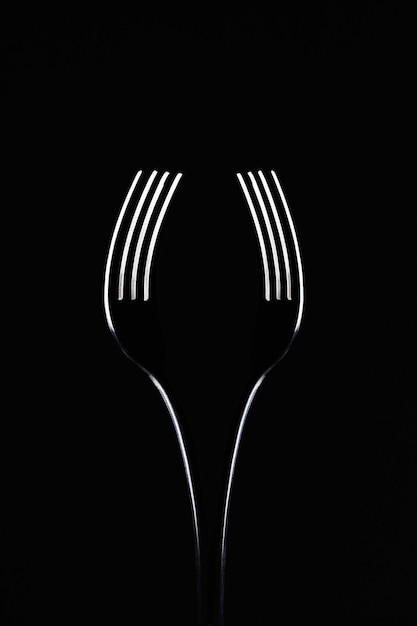 pair of forks on black background look like a wine glass