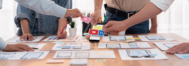 Panorama shot of frontend developer team brainstorming UI and UX designs for mobile app on paper wireframe interface User interface development team planning for userfriendly UI design Scrutinize