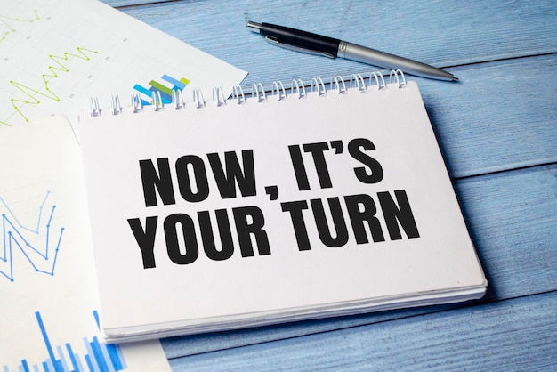 pen and a sheet of white paper with the text NOW ITS YOUR TURN