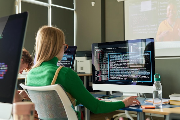 Pige sidder ved skrivebord med computer