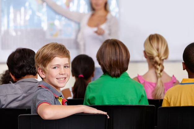 Portrait happy boy or student in classroom for knowledge education or development for future growth Smile back to school or child in chair for studying listening or fun learning for scholarship