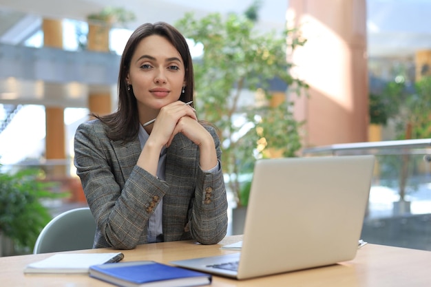 Portrait of a young brunette business woman using laptop at office