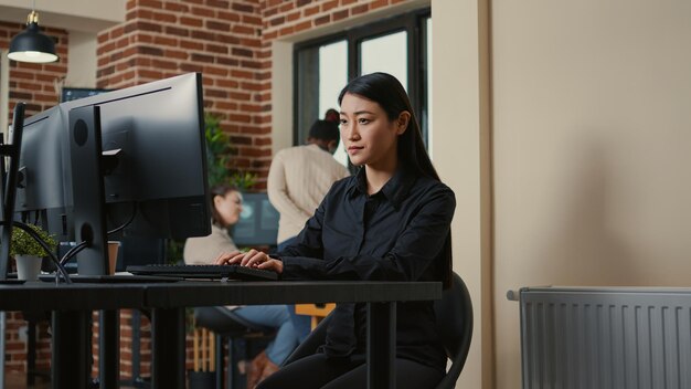 Portrait of focused system engineer happy with parsing results sitting at desk in software development office. Programer writing algorithm smiling after successfuly compiling source code.