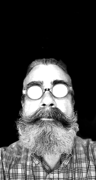 portrait of man wearing eyeglasses against black background