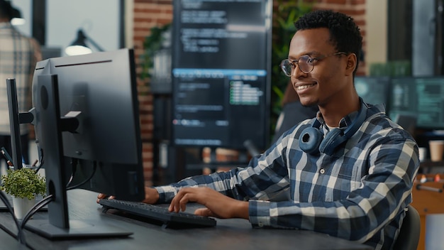 Portrait of software engineer writing code arranging glasses and being happy about parsing results. Smiling programer typing machine learning algorithm on keyboard innovating cyber security.