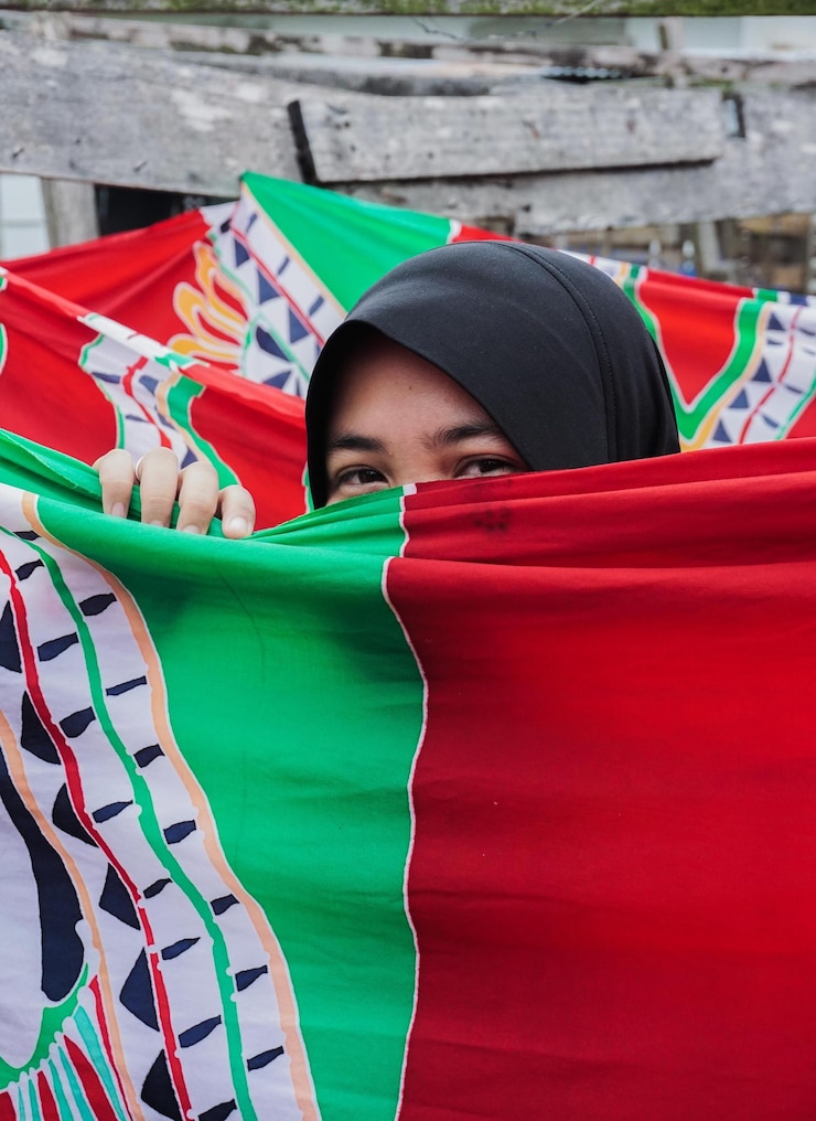 Bild portrait of woman wearing hijab looking through colorful curtain