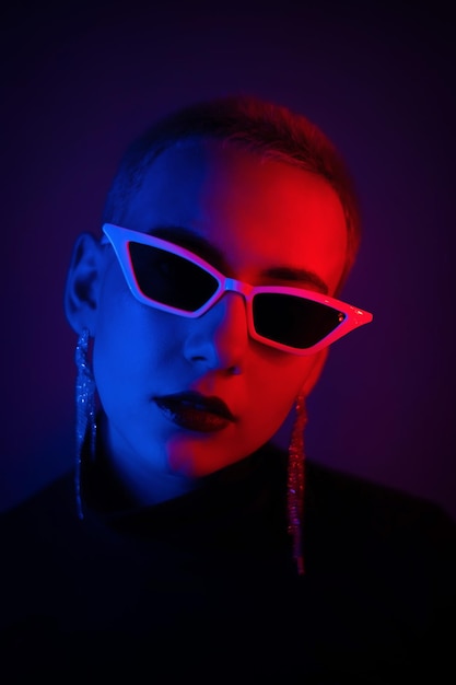 portrait of woman wearing sunglasses against black background