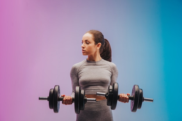 portrait of young fit and sportive caucasian woman on gradient background