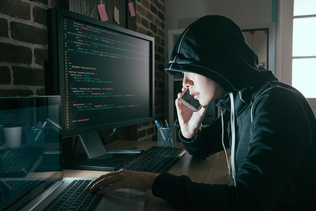 Professionell hackerkvinna dolt ansikte med mobiltelefon som pratar med offret begär lösen när hon sprider dåligt datavirus online.