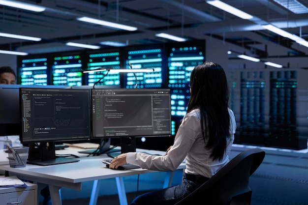Programmer in data center checking equipment performance on computer