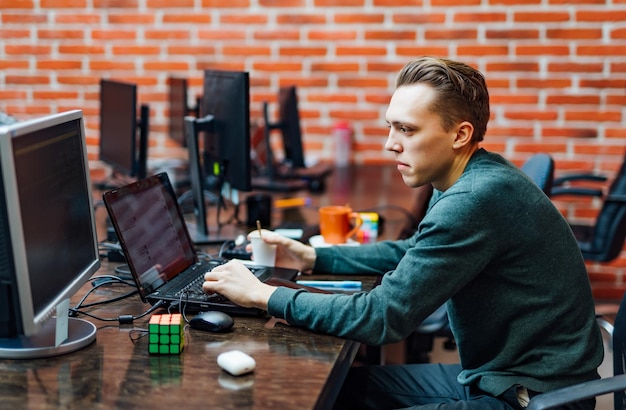 Programmer sitting at a desk with modern technologies and thinking of developing programming Man working in a software develop company office writing codes and typing data code