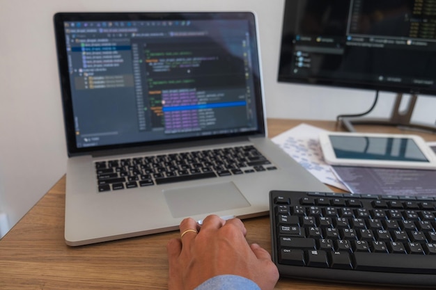 Programmer using laptop and computer on table