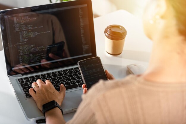 Programmerare kvinna tittar på mobiltelefonens programkod på arbetsplatsen