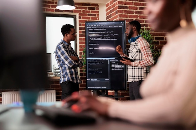 programming engineers analyzing html code standing in front of big screen, checking errors in artificial intelligence project. software developers working on machine learning software in it agency