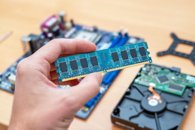 RAM memory module in hand Motherboard and hard disk in background Concept of installation