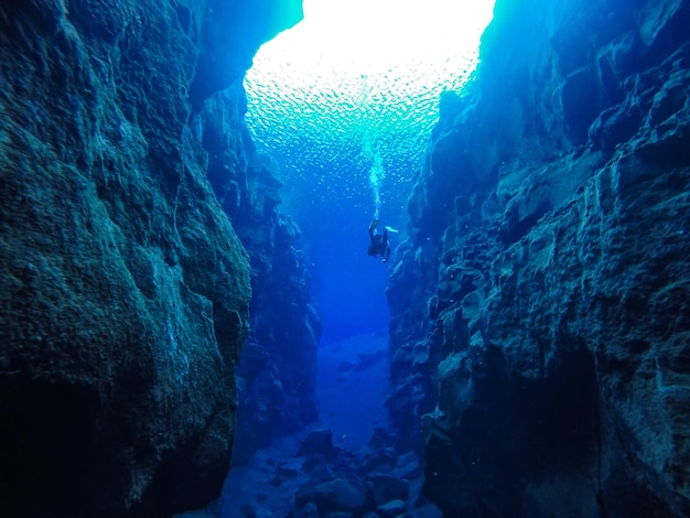 Scuba diver swimming amidst rock formations undersea