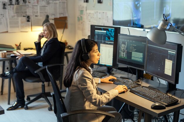 Serious agent of intelligence service sitting in front of computer monitors