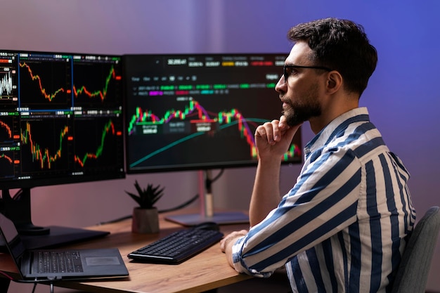 serious trader looking at computer monitor working online with crypto chart sitting in office