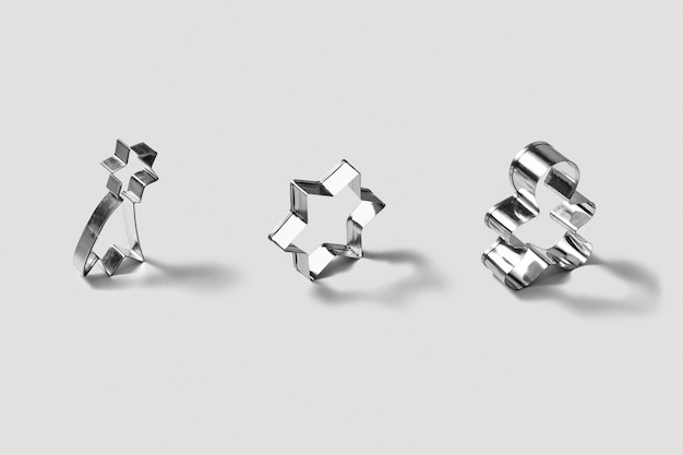 Set of stainless steel cookie-cutters for baking homemade christmas cookies, in the shape of stars and gingerbread on a light grey background with soft shadows.