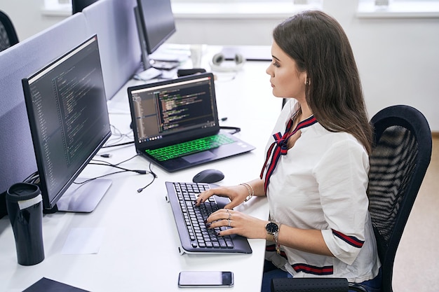 Sidevisning af kvinde, der bruger bærbar computer på kontoret