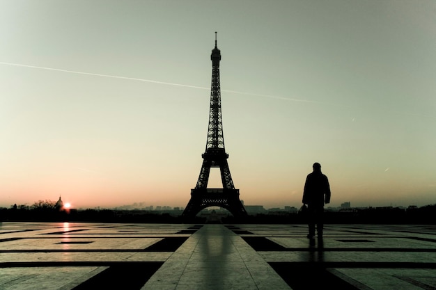 silhouette man with eiffel tower against sky during sunset