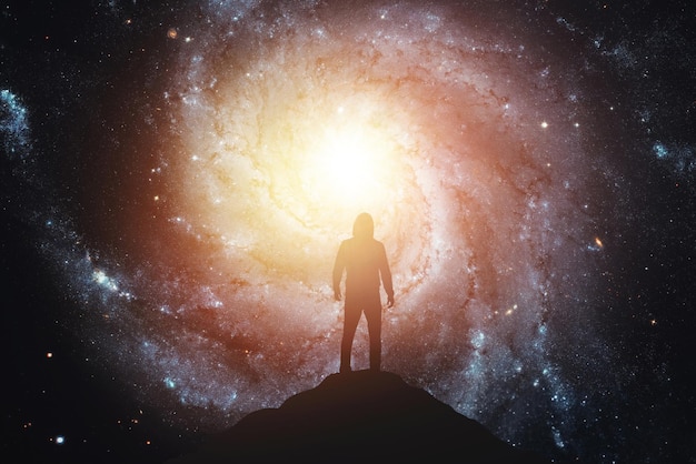 Silhouette of a man standing on the top of a mountain Elements of this image furnished by NASA