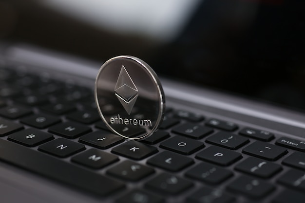 Silver ethereum coin is lying on laptop