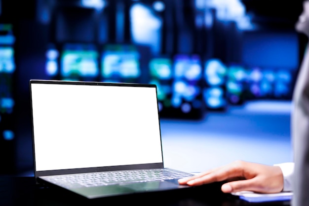 Skillful admin using mock up laptop to inspect data center mainframes with high computing power enabling server farm to support demanding applications including video rendering workloads close up