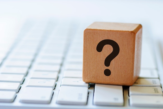 Small wooden dice with question mark on keyboard